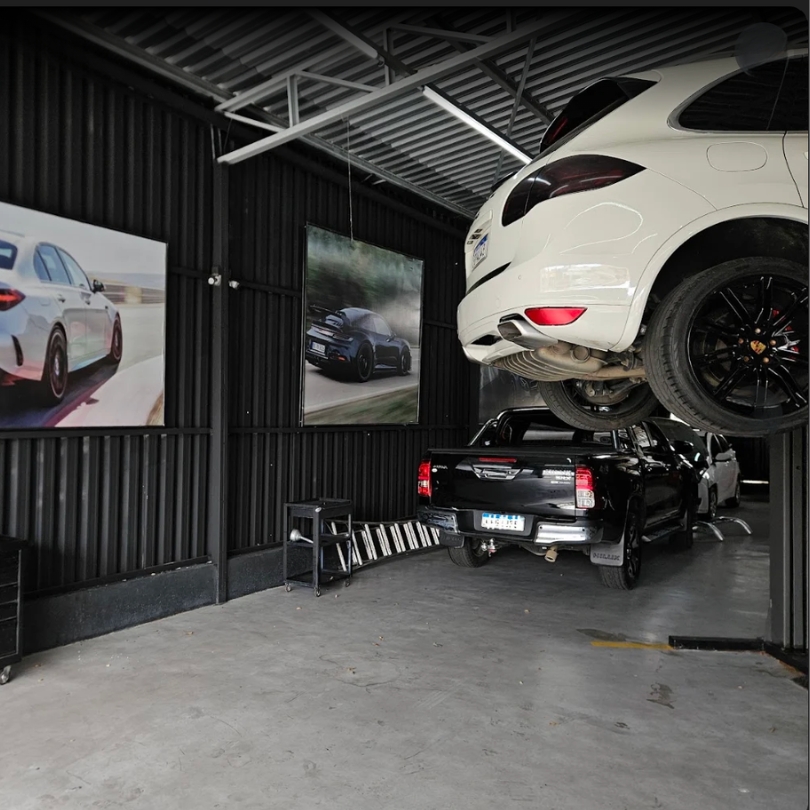 Porsche Cayenne elevado e outros veículos no box da oficina